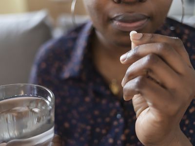 person taking a pill with a glass of water