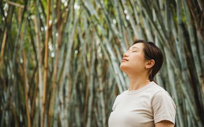 woman relaxing and breathing in fresh air in a bamboo forest