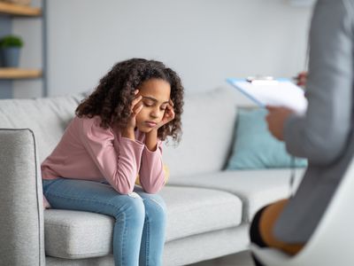 Unhappy girl listening to psychologist at meeting, thinking about her problems