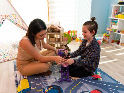 Little boy in child occupational therapy session doing sensory playful exercises with his therapist