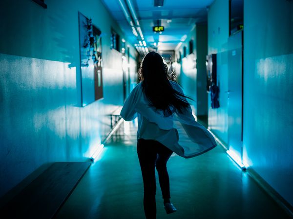 Rear view of female doctor rushing down the corridor of the hospital ward