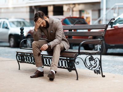 Man in despair, sitting on a bench, holding his head