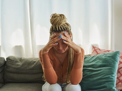 Shot of a young woman looking stressed on the sofa at home