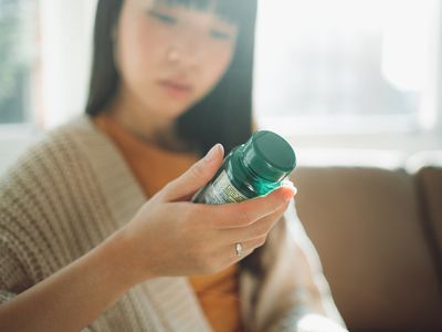 Woman reading a supplement bottle.