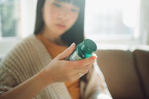 Woman reading a supplement bottle.