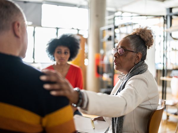 Senior woman comforting a mature man in group therapy