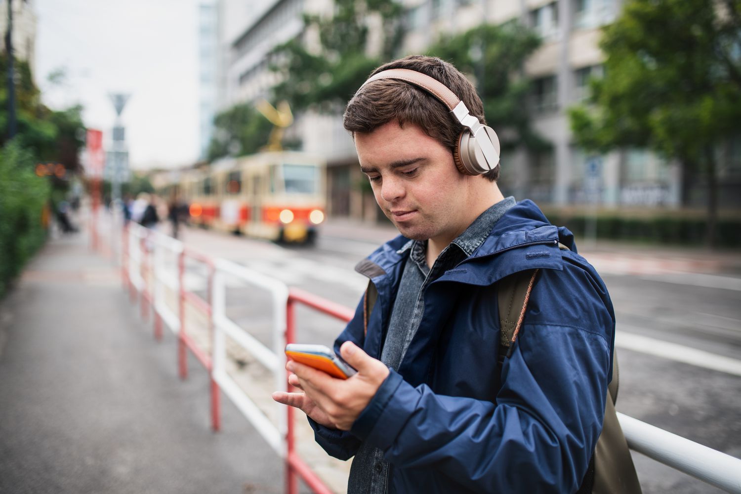 Portrait of young man with special needs outdoors in town.