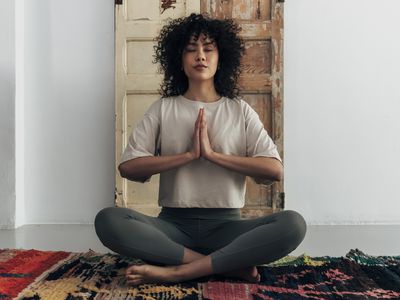 Multiracial young woman meditating with hands in prayer at home. Meditation concept. Spirituality concept.