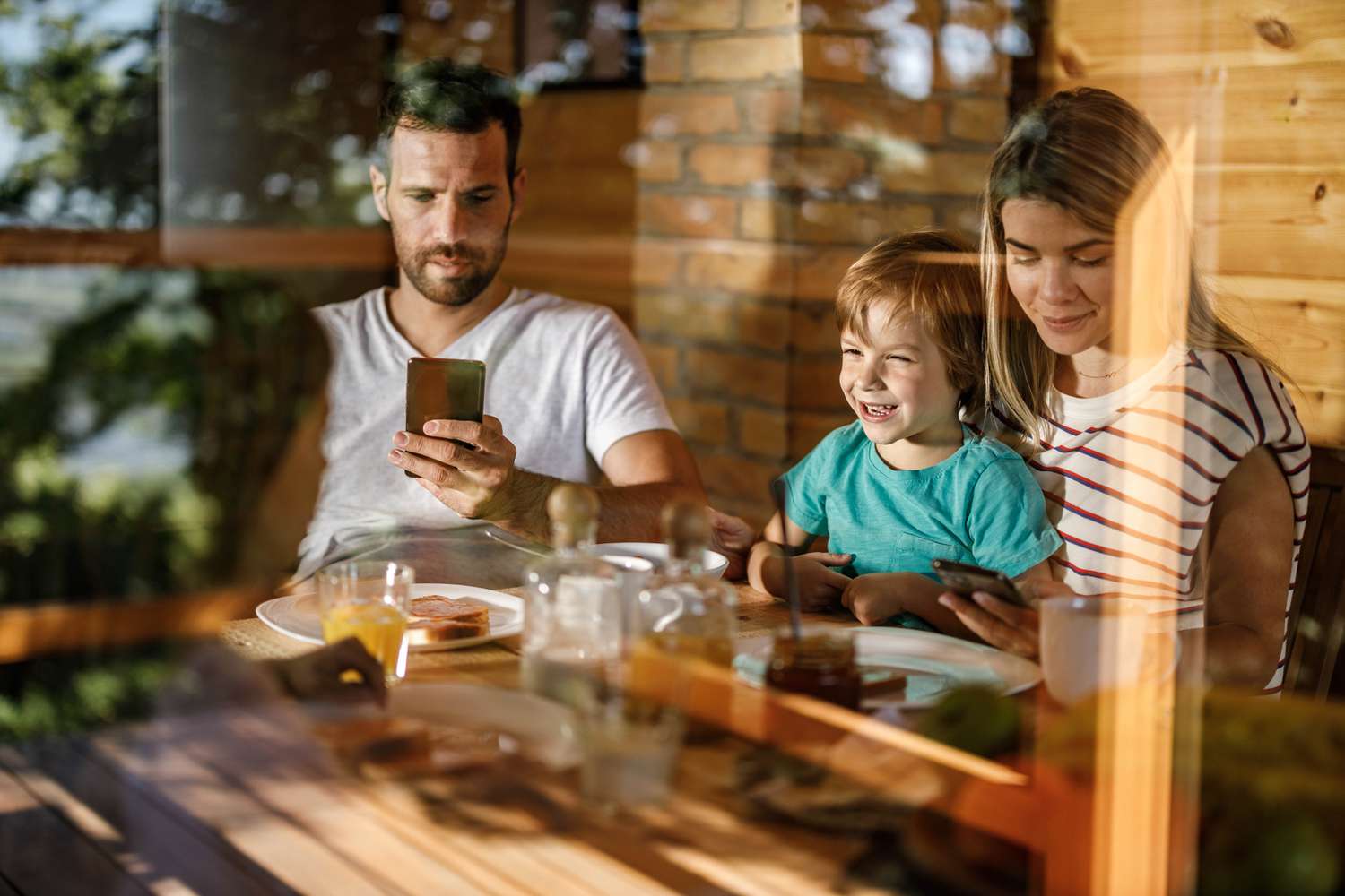 Careless parents using their smart phone while having breakfast with their kids in dining room