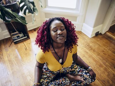 Content young woman sitting on floor meditating at home