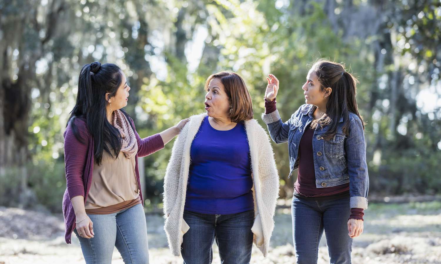 Senior Hispanic woman with adults daughters walk in park