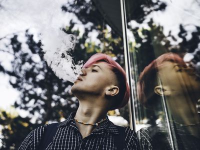 Young hipster with pink colored hair is smoking vape