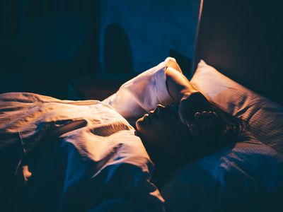 Woman with Insomnia. Young woman lying on bed with hand on forehead.