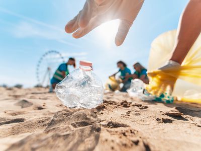 Group of eco volunteers picking up plastic trash on the beach - Activist people collecting garbage protecting the planet - Ocean pollution, environmental conservation and ecology concept