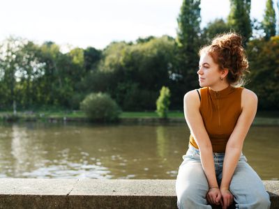 woman sitting on a wall next to a river