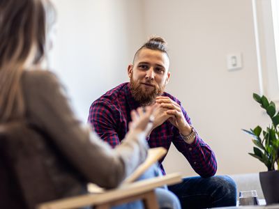 Female psychologist talking to young man during session.