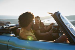 Young woman laughing while talking with boyfriend sitting in convertible car