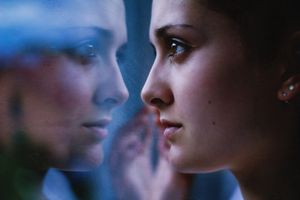 Woman's face close up, staring in mirror with reflection.