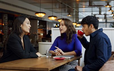 Small group of business colleagues sitting at table in cafe drinking coffee and talking during business meeting, togetherness, discussion, meeting