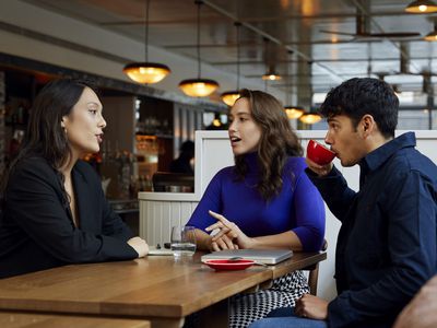 Small group of business colleagues sitting at table in cafe drinking coffee and talking during business meeting, togetherness, discussion, meeting