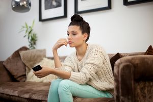 woman thinking on couch holding her phone