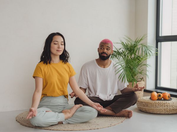 The guy doesn't really want to meditate and looks at his girlfriend with the thought that it' time to finish