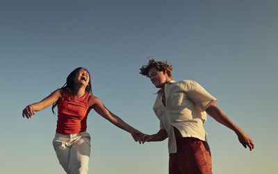 Low angle view of happy friends enjoying against clear blue sky