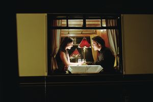 Young couple at table aboard train, exterior view, night