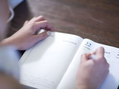 person writing in an agenda book