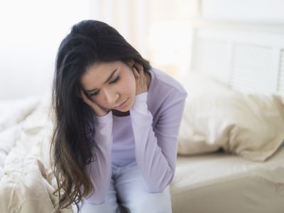 sad and anxious woman sitting at the end of her bed