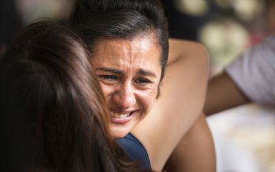 Woman crying with other woman hugging her.