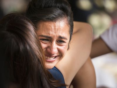 Woman crying with other woman hugging her.