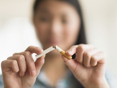 Woman breaking cigarette in half, quitting smoking.