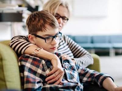 Mother sitting on a couch with her arm around her son