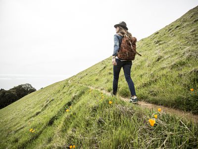 A woman with a backpack and hat on standing at a lookout