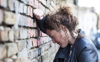 Woman leaning against brick wall