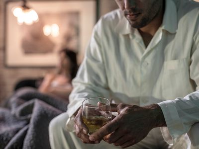 Man sitting on bed having a drink