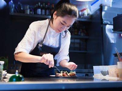 Chef in commercial kitchen seasoning food