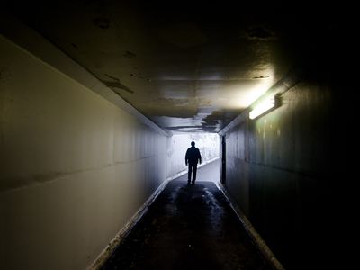 Silhouette of a man walking in a tunnel.