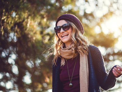 Woman walking outdoors while smiling.