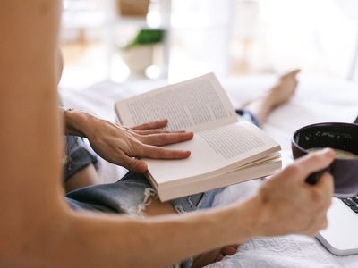 woman reading a book with coffee cup in hand