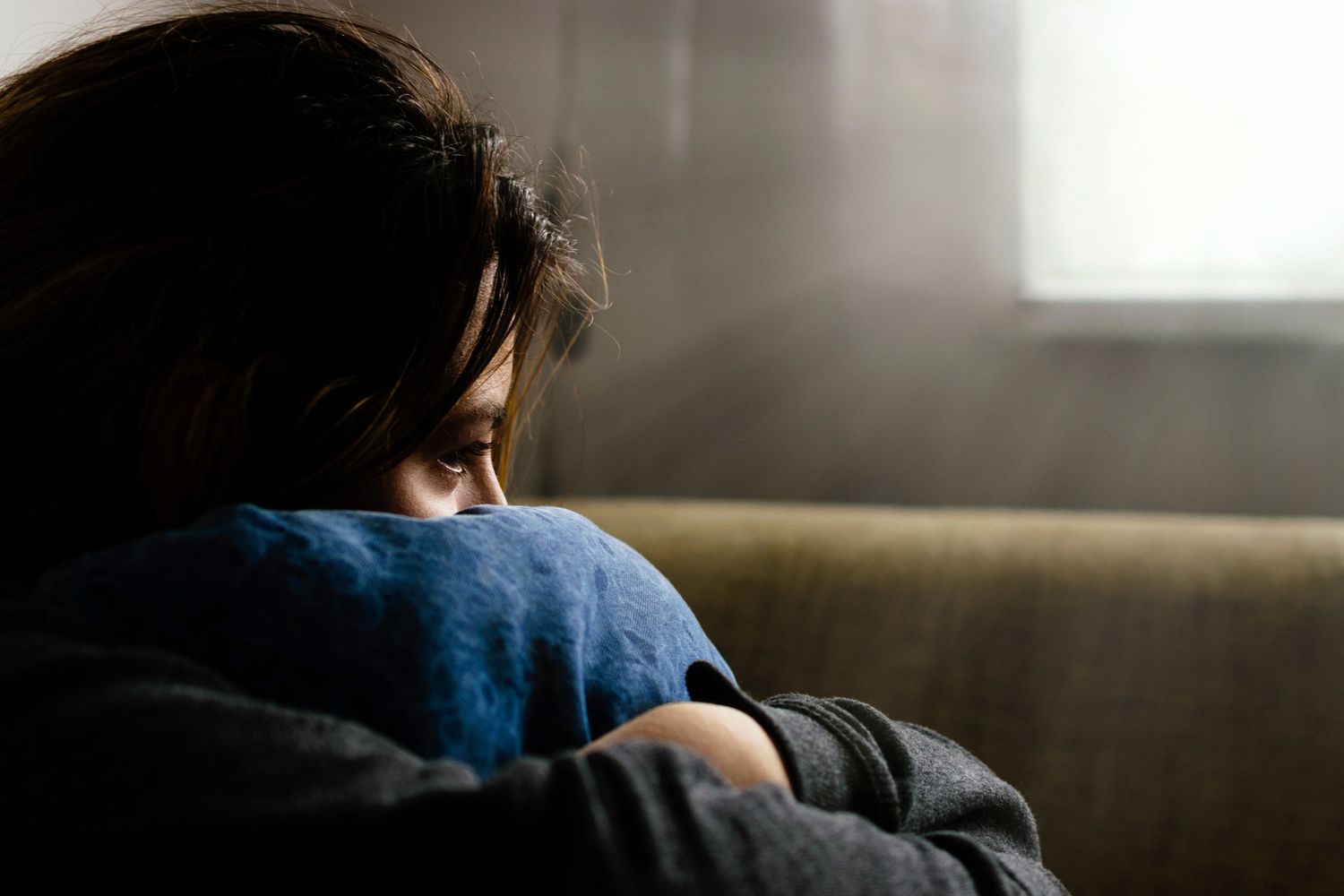 person depressed hugging their pillow on a couch