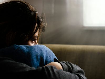 Sad Woman Hugging Cushion While Sitting At Home