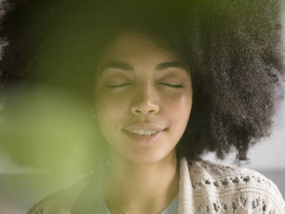 woman with afro closing her eyes and thinking