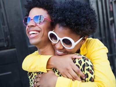 a smiling young woman hugging her laughing boyfriend from behind