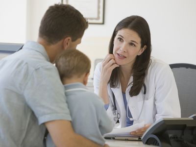 Female doctor talking to father and son