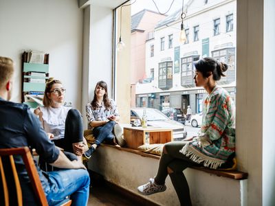 A group of friends are sitting down, relaxing and chatting with each other in a cafe.