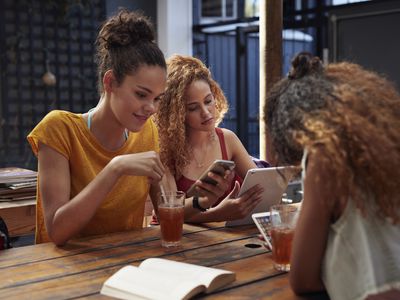 Young women sitting together on their devices