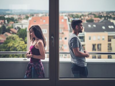 Sad couple standing back to back on a penthouse terrace