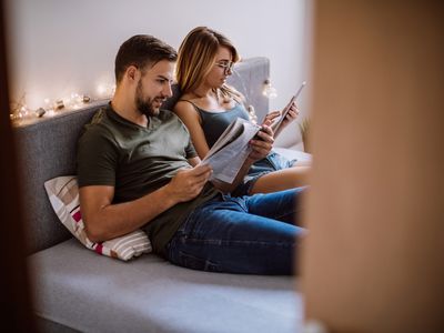 Couple reading newspaper and tablet in bed